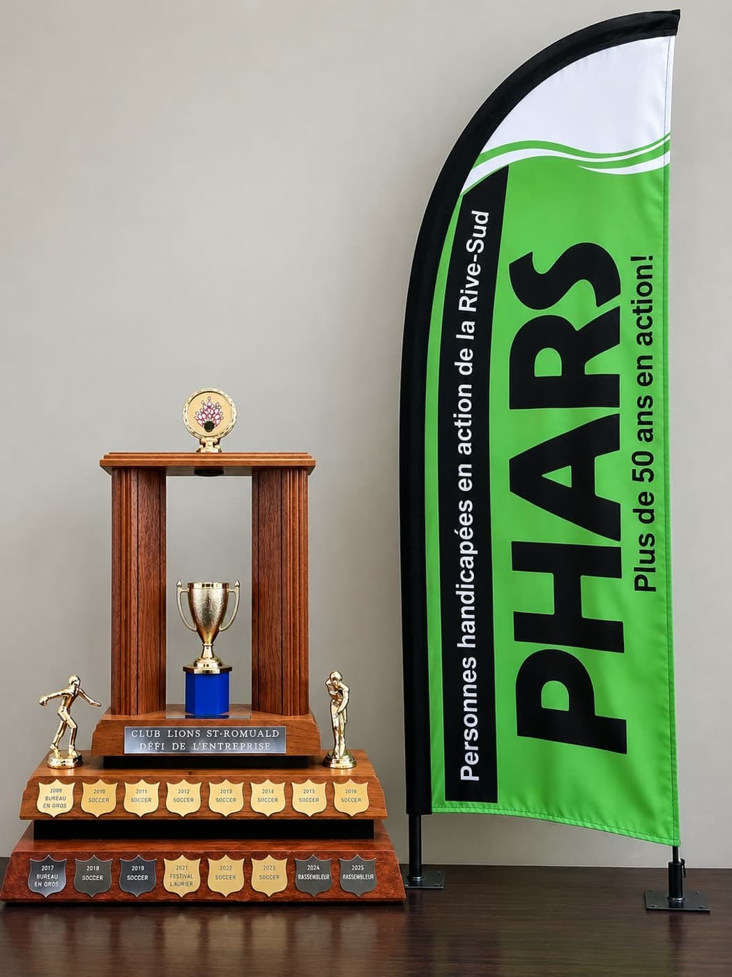 Le trophée du Défi de l'entreprise du Club Lions de Saint-Romuald, à côté de l'oriflamme de PHARS.